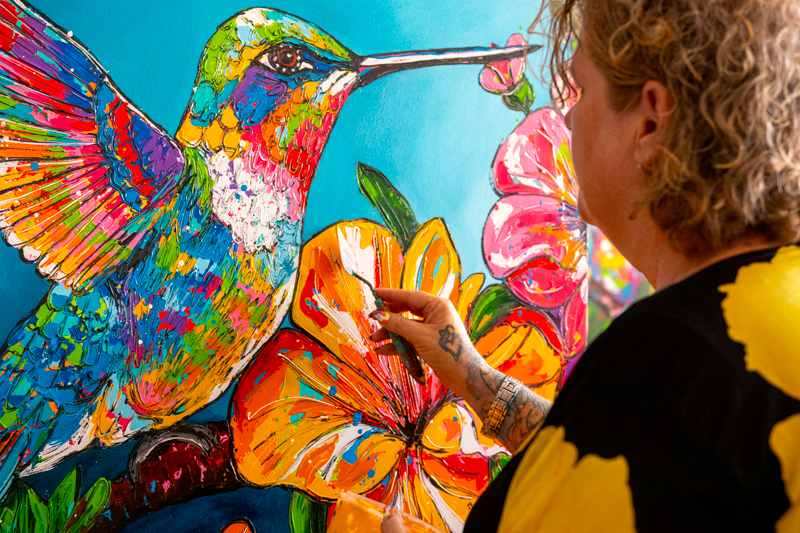 Renata painting a vibrant hummingbird and flowers